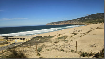 A sandy beach with a fence and waves