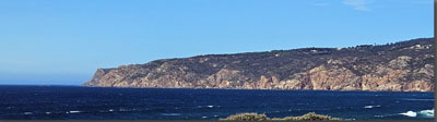 A body of water with a hill in the background